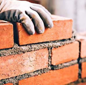 Albañil colocando un ladrillo en la construcción de un muro