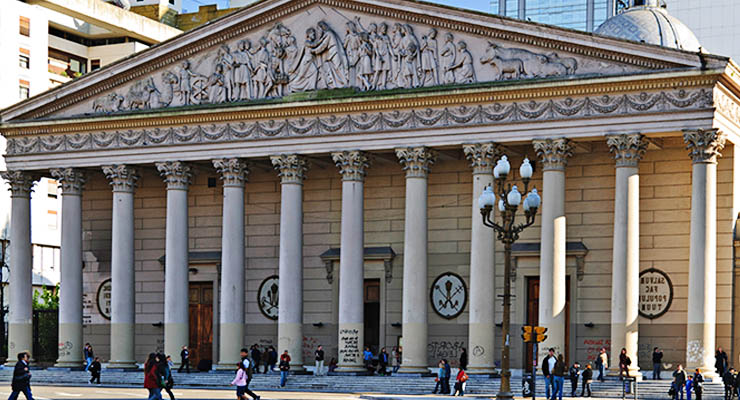 Fachada de un edificio clásico compuesta por columnas y frontón triangular adornado con esculturas